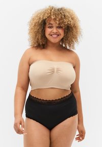 Bežs strapless tops ar saplacinātu centru, kombinēts ar augsta vidukļa melnām biksītēm ar mežģīņu apdari jostas vietā.