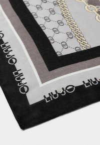 Foulard en soie carré présentant un motif géométrique en noir, gris et blanc, avec un design de chaînes et de petites accents en strass.