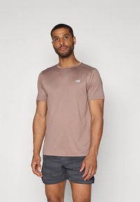 Tricou sport maro deschis cu mâneci scurte, gât rotund și un mic logo albastru pe pieptul stâng, asortat cu pantaloni scurți cu model.