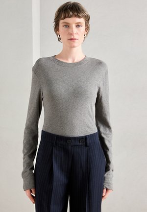 Gray long-sleeve top made of soft fabric, featuring a crew neckline, paired with navy pinstripe trousers and double-button front detail.