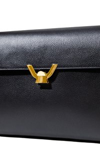 Una borsa a mano in pelle nera lucida presenta una distintiva chiusura dorata con un design a forma di Y, mettendo in risalto il suo stile elegante e moderno.