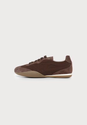 Baskets basses en daim et cuir marron avec lacets, bout arrondi et semelle en caoutchouc beige, vues de côté extérieur sur un fond uni.