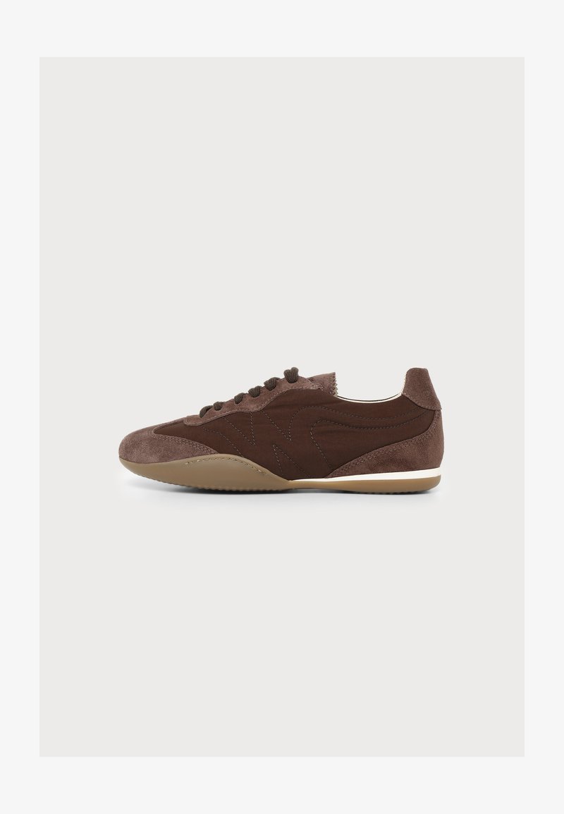 Καφέ καστόρινο και δερμάτινο sneaker χαμηλού προφίλ με κορδόνια, στρογγυλεμένη μύτη και μπεζ λάστιχο σόλα, εμφανιζόμενο από την εξωτερική πλευρά σε απέριττο φόντο.