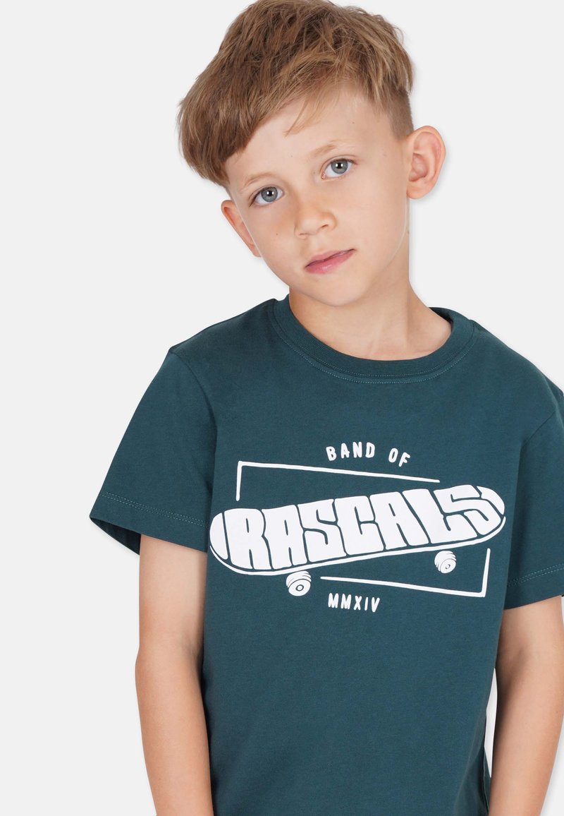 Teal Baumwoll-T-Shirt mit einem weißen Grafikdesign, das den Text "BAND OF RASCALS" und ein Skateboard-Motiv zeigt. Kurze Ärmel und runder Ausschnitt.