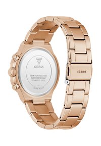 Montre-bracelet Guess en acier inoxydable rose gold avec fermoir fermé et dos affichant des détails sur la résistance à l'eau et le mouvement japonais.