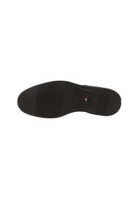 Semelle noire d'une chaussure habillée avec des motifs de grip texturés, semelle marquée "Fabriqué en Italie" et un petit drapeau italien.