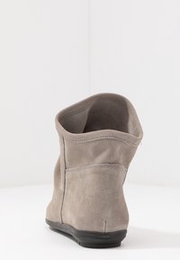Stivaletto alla caviglia in suede grigio con una texture liscia, cima arrotondata e dettagli di cucitura minimi. Suola in gomma nera bassa. Vista posteriore che mostra l'interno.