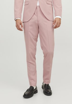 Svetlo roza krojene hlače s slim fit krojem, iz gladkega materiala, z stranskimi žepi in diskretnimi pregibi, v kombinaciji z črnimi loaferji.