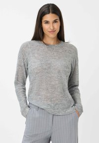 Helles graues Pullover-Sweatshirt mit strukturiertem Finish und subtilen Glitzerelementen. Mit Rundhalsausschnitt und geripptem Saum, kombiniert mit grauen Nadelstreifen-Hosen.