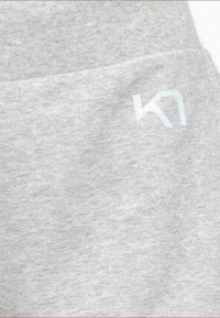 Graue Jogginghose mit weicher Stoffstruktur, elastischem Bund und einem dezenten reflektierenden Logo in der unteren Ecke.