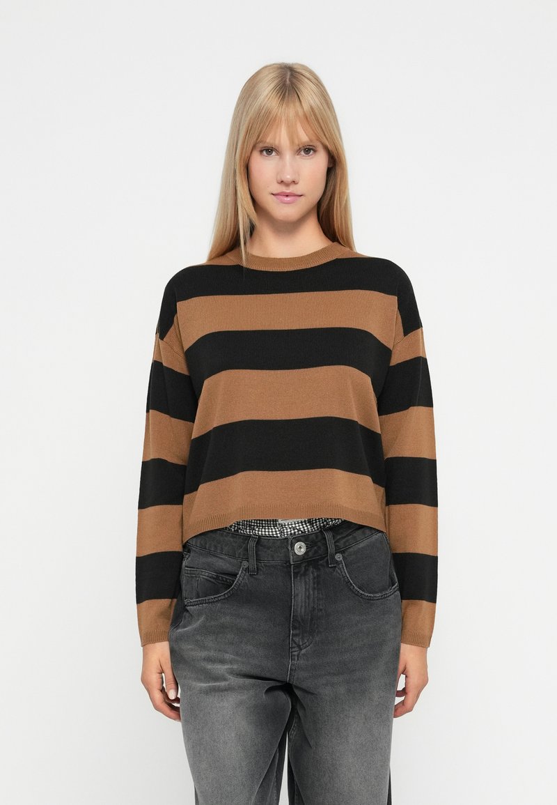 Black and brown striped cropped sweater with long sleeves, ribbed texture, round neckline, worn over black high-waisted jeans.
