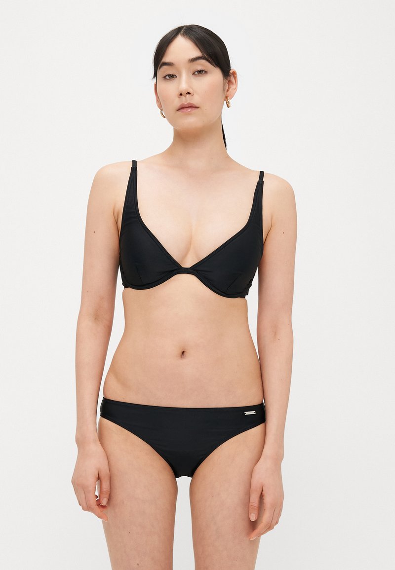 Σετ μαύρου μπικίνι που περιλαμβάνει τοπ με τριγωνικό σχήμα και ρυθμιζόμενους ιμάντες, καθώς και αντίστοιχο μπικίνι με χαμηλή μέση. Λείο ύφασμα με ελάχιστα μεταλλικά στοιχεία.