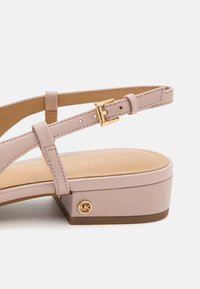 Sandal in rosa chiaro con tomaia in pelle liscia, cinturino alla caviglia regolabile, fibbia dorata e un tacco a blocco spesso con un accento del logo.