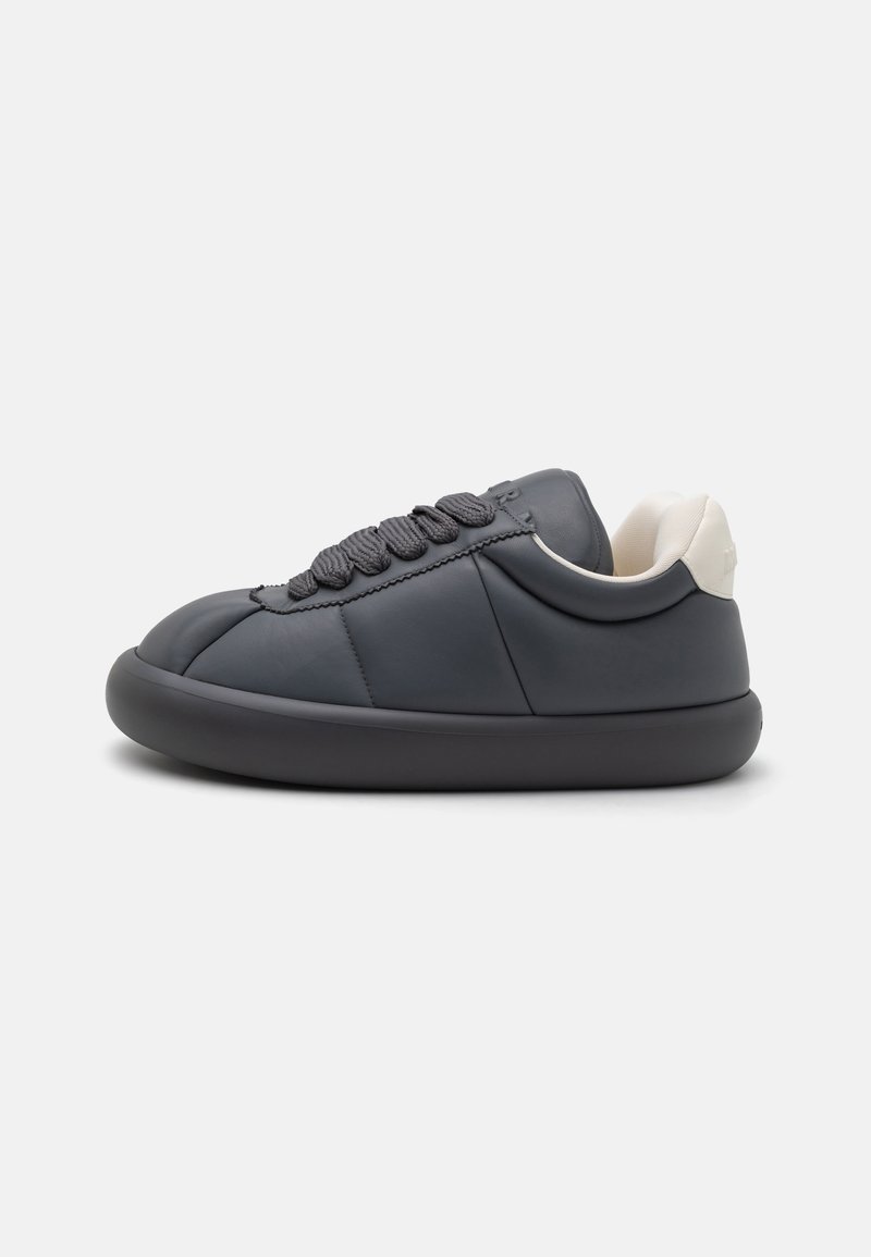 Gray leather sneaker with a rounded toe, thick rubber sole, and textured gray laces. Features a cream-colored accent at the heel.