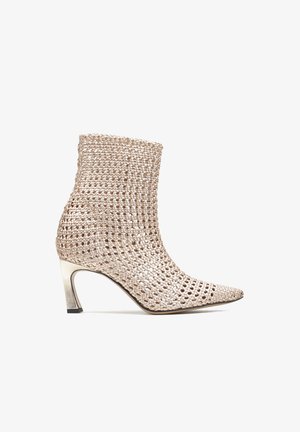 Tkany metaliczny botek na kostkę z ostrym noskiem i smukłym obcasem średniej wysokości, charakteryzujący się ażurowym wzorem i błyszczącym wykończeniem.