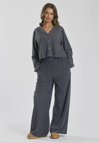 Grå loungewear-sæt med en cropped top med knaplukning fortil og vide bukser, lavet af blødt, tekstureret stof. Casual og afslappet pasform.