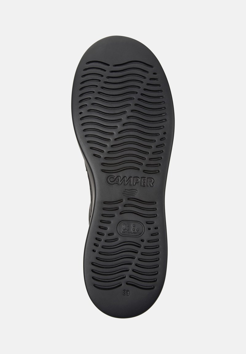 Schwarze Schuhsohle mit strukturiertem Design, auf dem der Markenname "CAMPER" und die Schuhgröße "38" sichtbar sind.