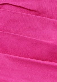 Tissu fuchsia avec une surface texturée, présenté en plis superposés. Le matériau semble doux, avec une teinte uniforme partout.