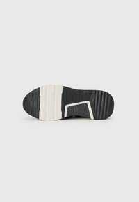 Semelle de sneaker noire en caoutchouc texturé pour une meilleure adhérence, avec des accents crème et un design moulé pour le confort. Détails de coupe et de motifs distinctifs.