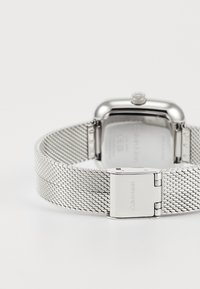 Montre bracelet en maille argentée avec boîtier rectangulaire, finition métal poli, et fermoir arborant un gravé "Calvin Klein".