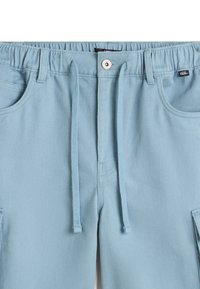 Lichtblauwe katoenen broek met een elastische tailleband, trekkoord, zijzakken en een klein logo-label. Subtiele diagonale textuur.