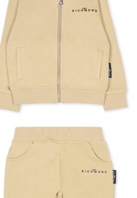 Haut à capuche zippé beige et pantalon assorti, avec des poignets et un ourlet côtelés, des poches latérales, et un branding sobre en noir près des zips.
