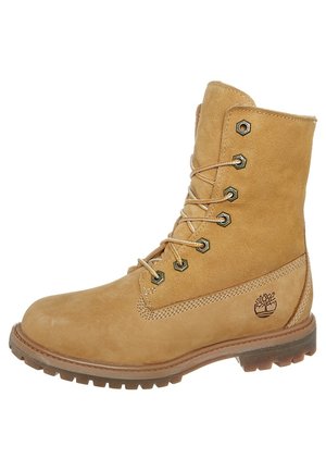 Tan leren veterschoen met robuuste zool, metalen oogjes, gestikte kraag en Timberland-boomlogo aan de zijkant.
