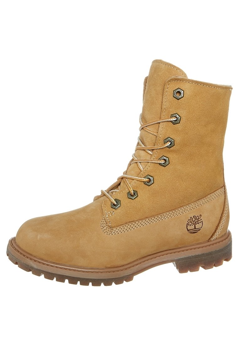 Bota de cuero marrón claro con cordones, suela resistente, ojetes de metal, cuello acolchado y logotipo del árbol Timberland en el lateral.