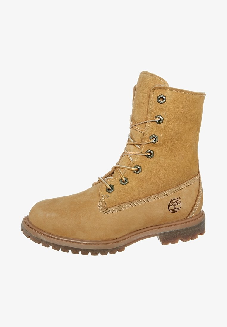 Bota de cuero marrón claro con cordones, suela resistente, ojetes de metal, cuello acolchado y logotipo del árbol Timberland en el lateral.