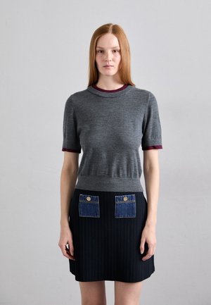 Grå kortermet genser med en maroon krage, kombinert med et svart ribbestrikket skjørt som har to denimlommer og gullknapper.