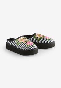 Czarno-białe wsuwane buty w paski z kwiatową haftowaną ozdobą i czarną gumową podeszwą; posiadają dekoracyjne przeszycia oraz zaokrąglony kształt noska.