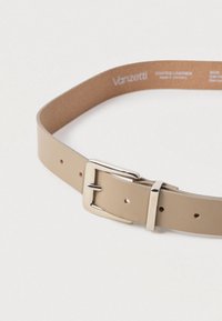 Beige nahkavyö hopeisella metallisoljella, jossa on useita säätöaukkoja ja sileä pinta.