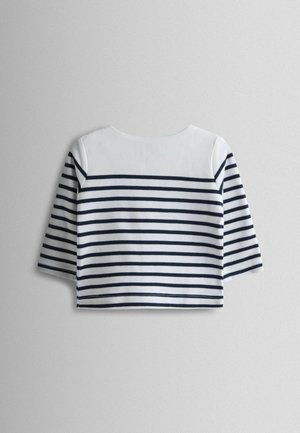 Triibuline lühike pluus, kus on tumesinised horisontaalsed triibud valgel kangal, ümar kaelus ja kolmveerandvarrukad. Pehme tekstuur.