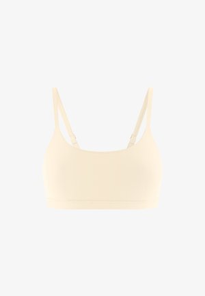 Bralette beige sans couture avec bretelles fines réglables, large bande sous la poitrine et tissu lisse et extensible.
