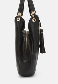 Svart läderväska med en slät yta, dragkedjestängning, rund form och hårdvara i guldton. Har ett fransdetalj på sidan.