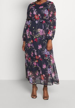 Lang, navy blomsterkjole med gennemsigtigt stof, der har livlige pink, røde og lilla blomster, lange ærmer og en taljebånd detalje.