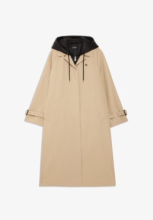 Beige raincoat with a black hood, featuring a relaxed fit, large front pockets, and adjustable wrist straps. Includes a detachable hood.