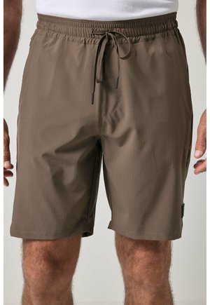 Brune knælange herreshorts med elastisk taljebånd og snøre, båret med en hvid t-shirt.