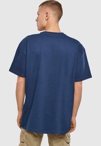 Marineblå oversized bomulds t-shirt med korte ærmer, rund hals og en glat tekstur, vist fra bagsiden.