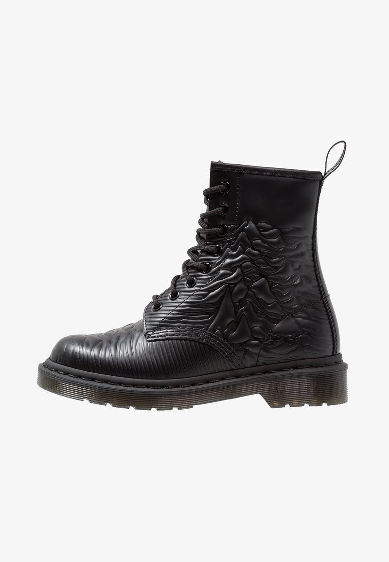 Bottine noire à lacets avec tige texturée présentant des motifs ondulés et côtelés, bout renforcé et semelle en caoutchouc. Ouverture avec languette au talon.
