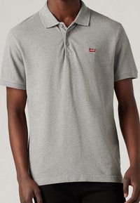 Polo gris en mélange de coton, doté d'un col classique, de deux boutons et d'un petit logo rouge Levi's sur la poitrine gauche.