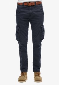 Pantalones cargo en azul marino con un ajuste relajado, presentan bolsillos laterales, detalles cosidos y un cinturón de cuero en tono marrón. Tejido texturizado.