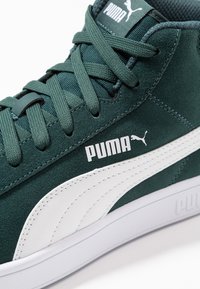 Zelené semišové vysoké tenisky s bílými koženými detaily, se strukturovaným jazykem, kulatými tkaničkami a výrazným logem Puma.