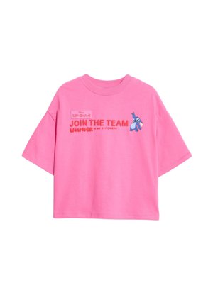 Różowy t-shirt z krótkim rękawem z haftowanym napisem i logo Disney, zestawiony z dużymi różowymi okularami przeciwsłonecznymi i teksturowanymi kręconymi włosami.