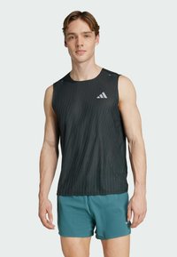 Schwarzes ärmelloses Sportshirt mit vertikaler Struktur, versehen mit einem kleinen weißen Adidas-Logo. Kombiniert mit türkisfarbenen Shorts, beide für den Sport ausgelegt.