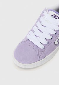 Purple suede sneaker with white laces, perforated toe, and contrasting gray logo accents. Low-profile rubber sole.