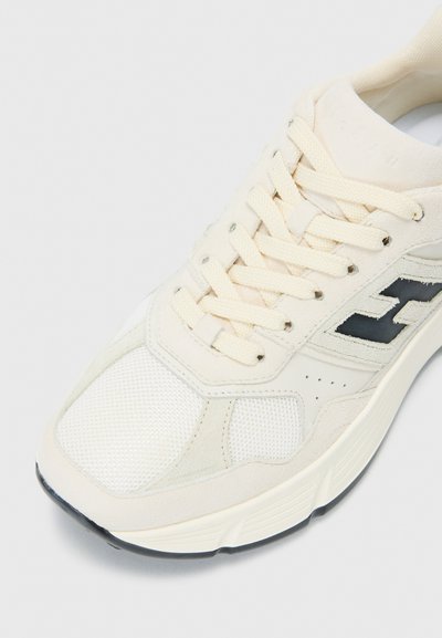 Lichtbeige sneaker van mesh en suede materiaal, met een zwart logo, ronde vorm, gestructureerde zool en crèmekleurige veters.