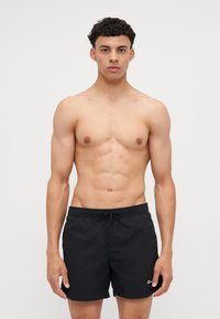 Shorts de bain noirs avec taille élastique et cordon de serrage. Fabriqués en tissu léger avec une texture douce. Présentent un petit logo sur la gauche.
