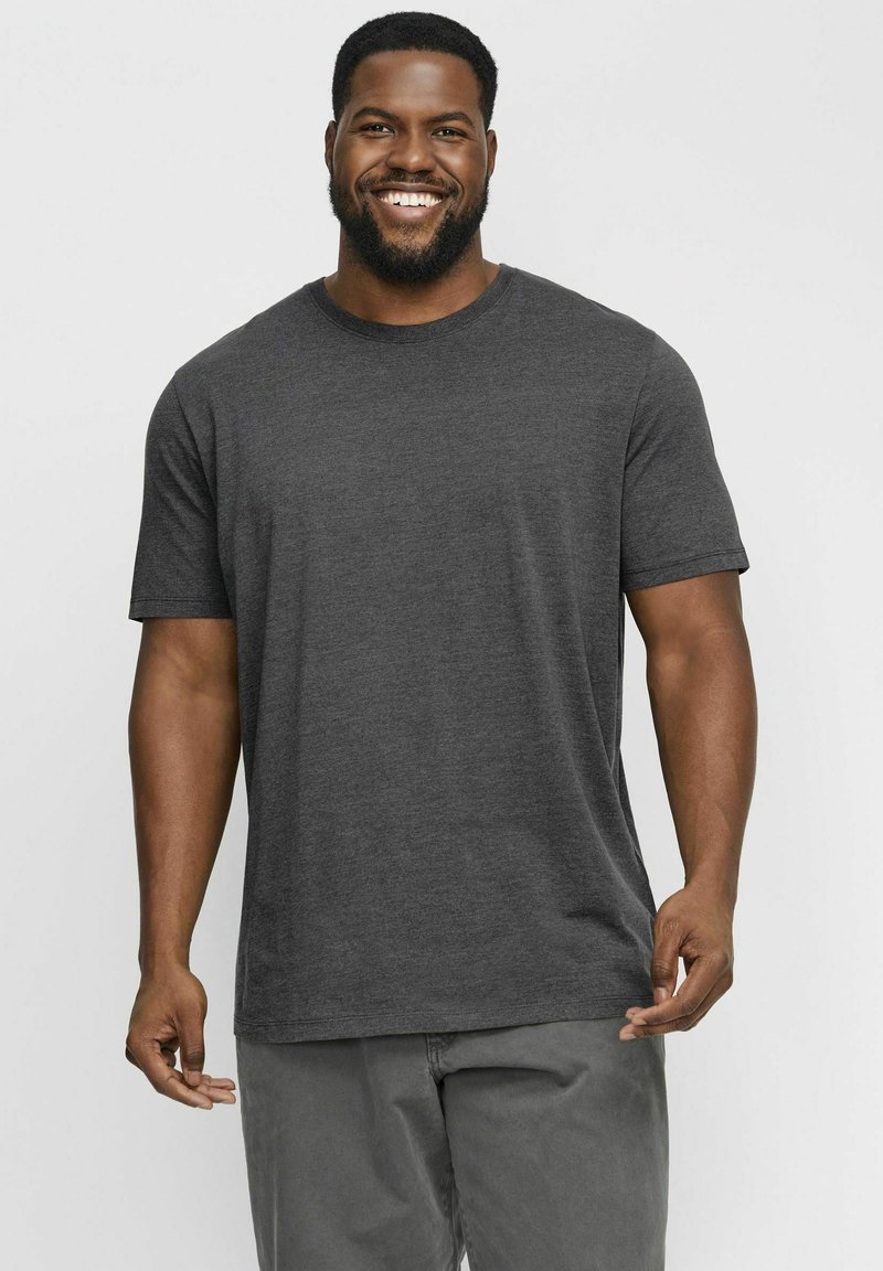 Camiseta de manga corta en gris oscuro, hecha de un tejido suave, con un cuello redondo y un corte relajado, combinada con pantalones grises claros.