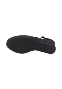 Zapato negro tipo slip-on con parte superior de tela texturizada, suela de goma y patrón acanalado. Presenta una punta redondeada y un diseño ligeramente elevado.